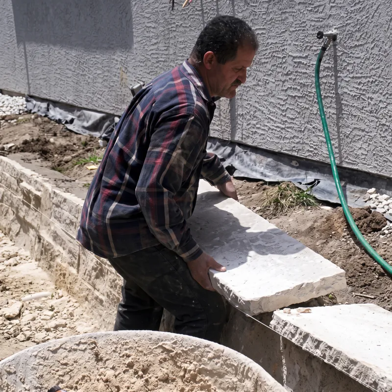 Veteran mason's weathered hands carefully laying a red clay brick